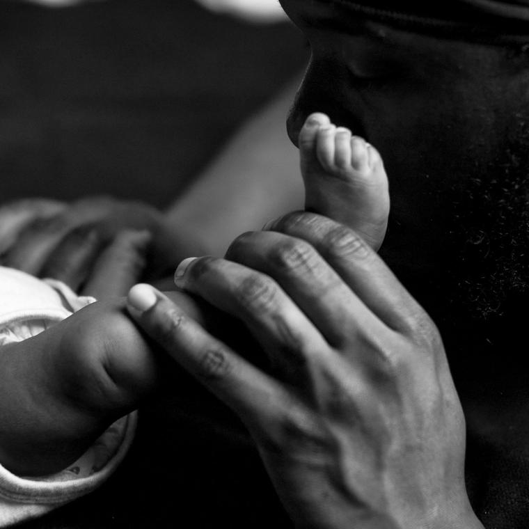 A father gently kisses his newborn's tiny foot